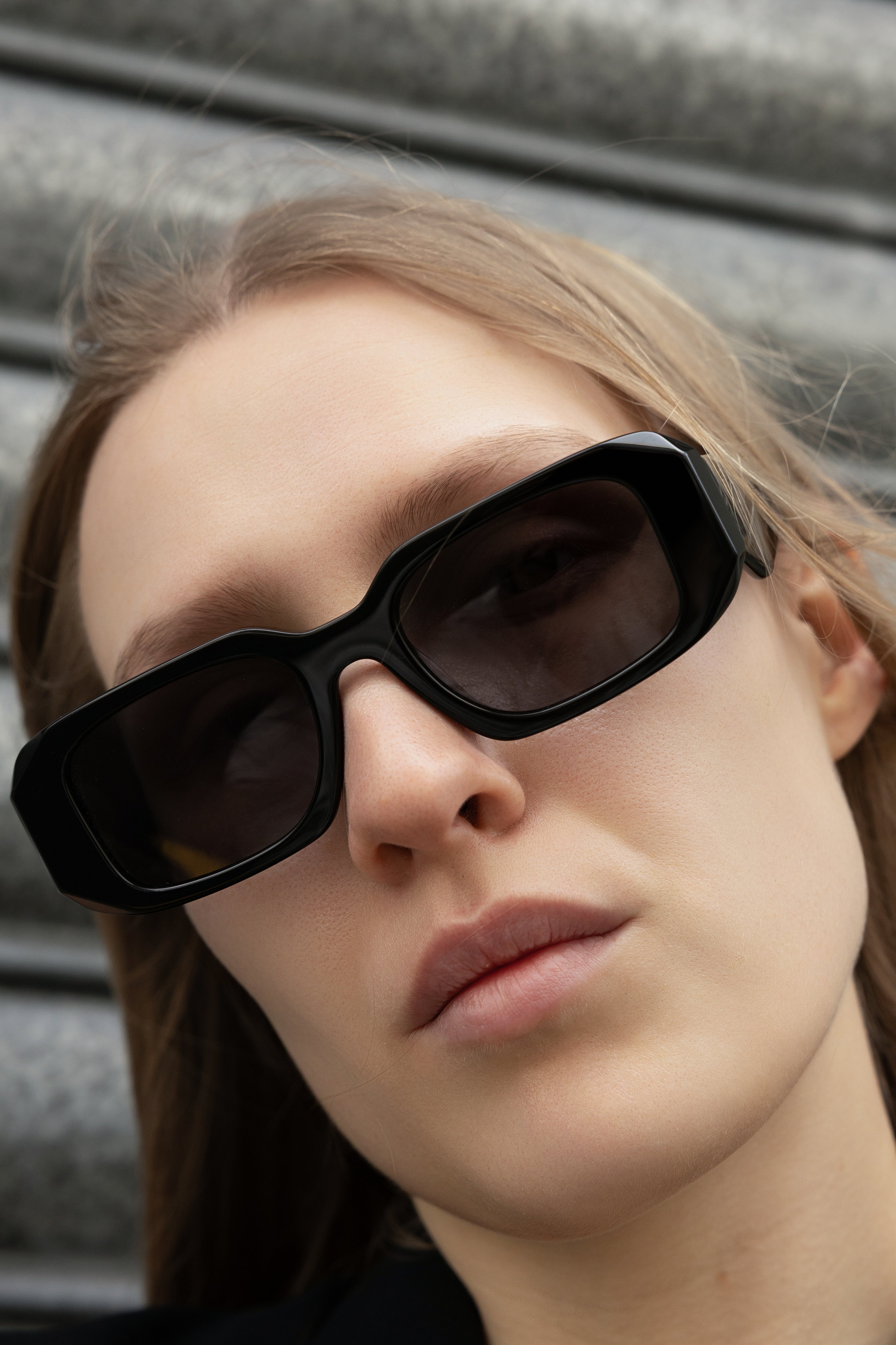 Close-up of a person wearing black minimalistic sunglasses in new zealand and australia with a blurred background